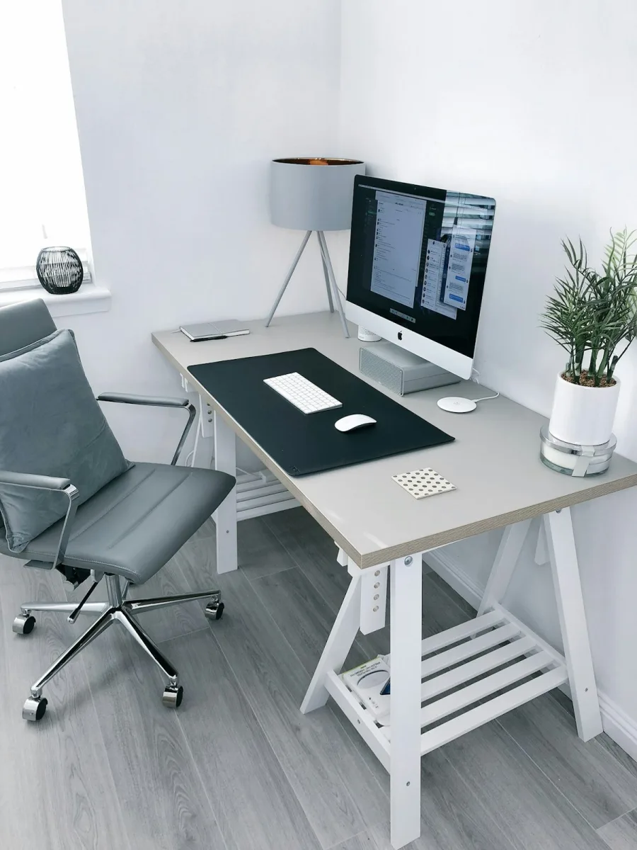 Aufgeräumter Schreibtisch mit Bildschirm, Tastatur und gepolstertem Bürostuhl